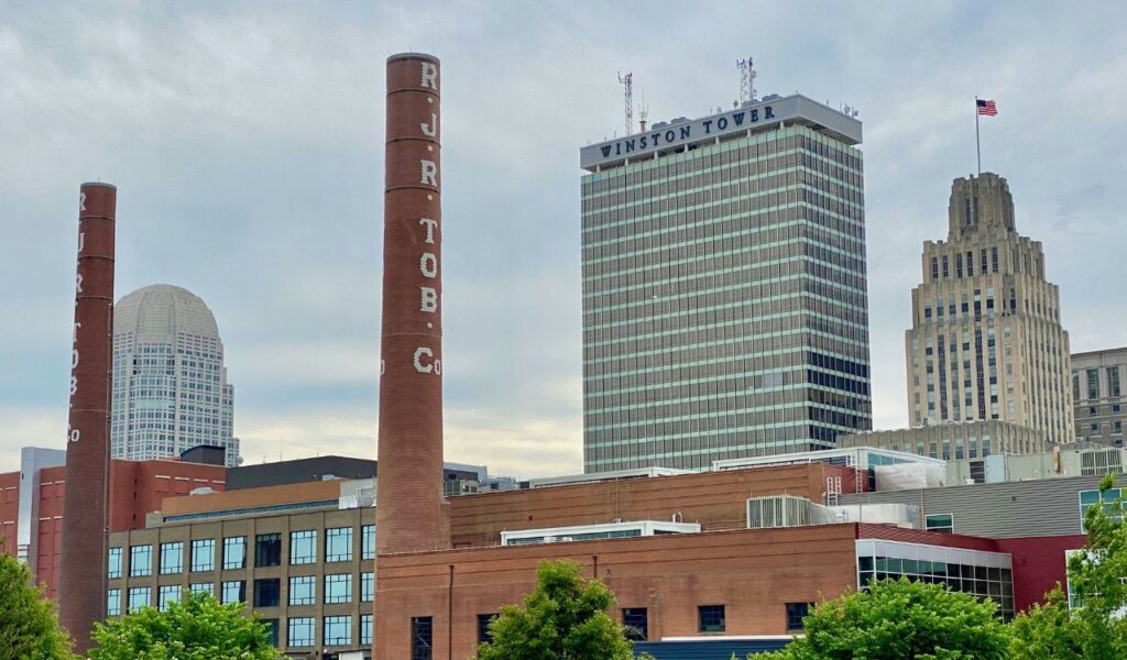 Downtown Winston-Salem, North Carolina skyline with historic R.J. Reynolds smokestacks and modern high-rise buildings.