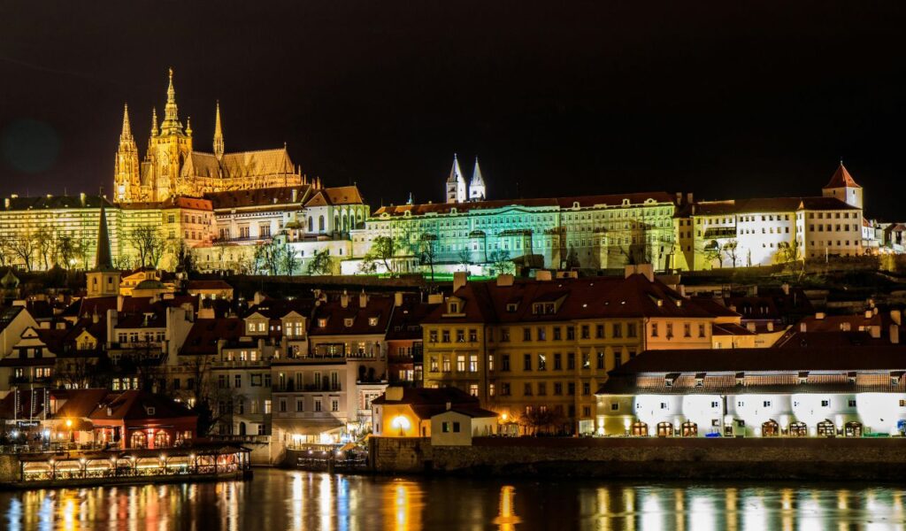 Zvíkov Castle in the Czech Republic lit up at night with its reflection on the river.