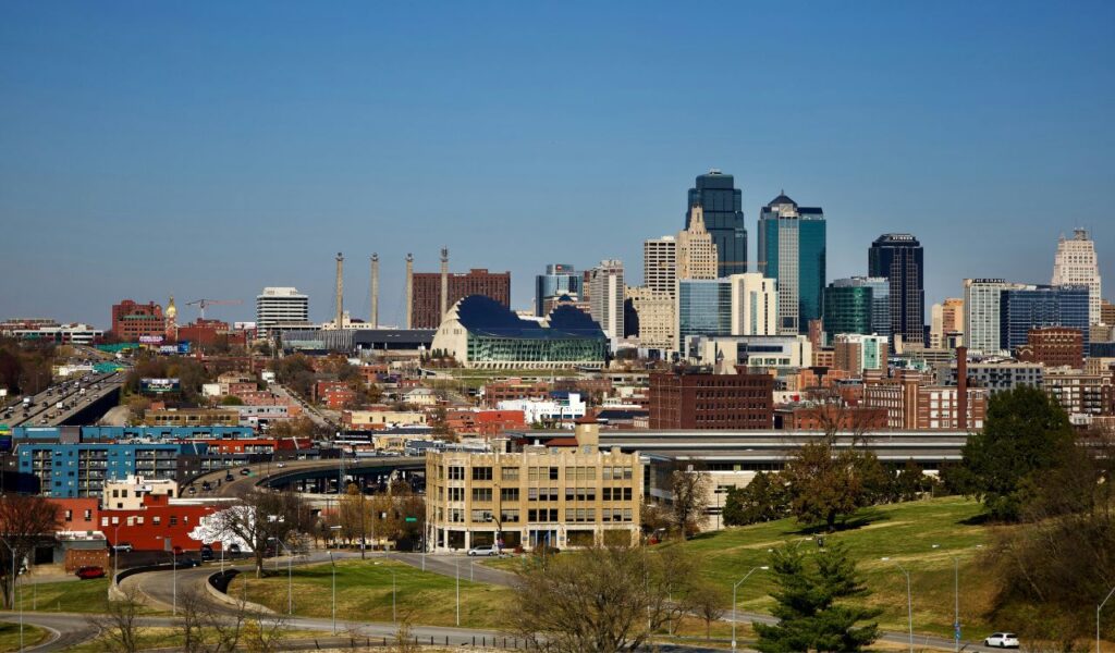 Cityscape of Dodge City, Kansas, with highways, buildings, and a skyline featuring modern and historic architecture under a clear blue sky.