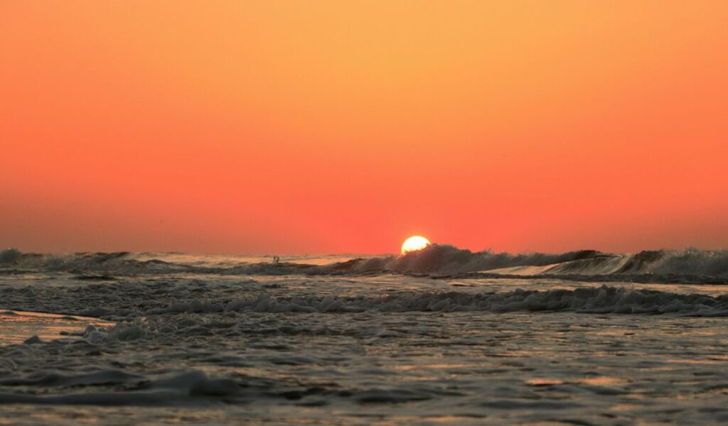 Golden sunrise over the ocean at Hilton Head Island, South Carolina, with gentle waves rolling toward the shore.