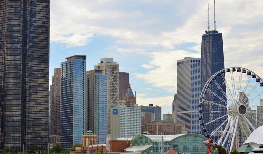 A large Ferris wheel stands near Chicago’s Navy Pier, set against a backdrop of towering skyscrapers including the John Hancock Center.