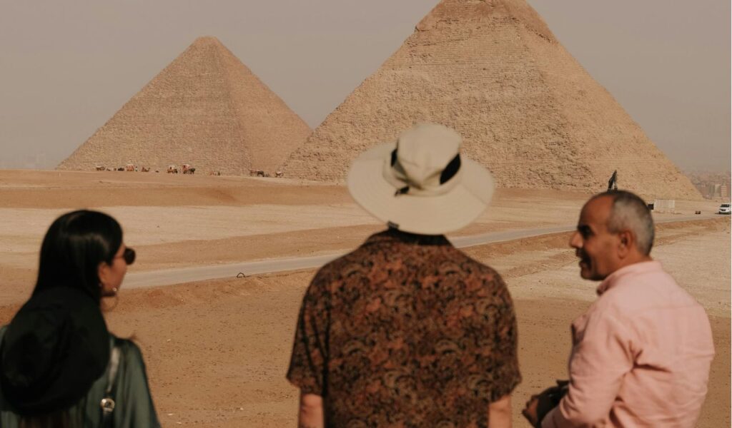Tourist conversing with a local guide near the pyramids in Egypt, learning basic Arabic phrases for better interaction.