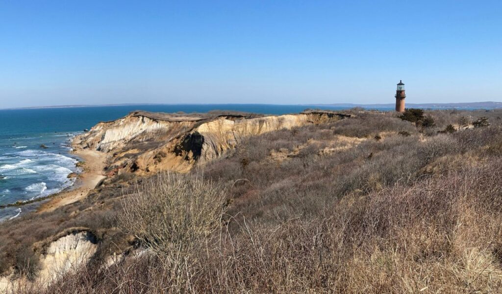 View of the Gay Head Cliffs and lighthouse on Martha’s Vineyard, Massachusetts, with the Atlantic Ocean and sandy beach below.