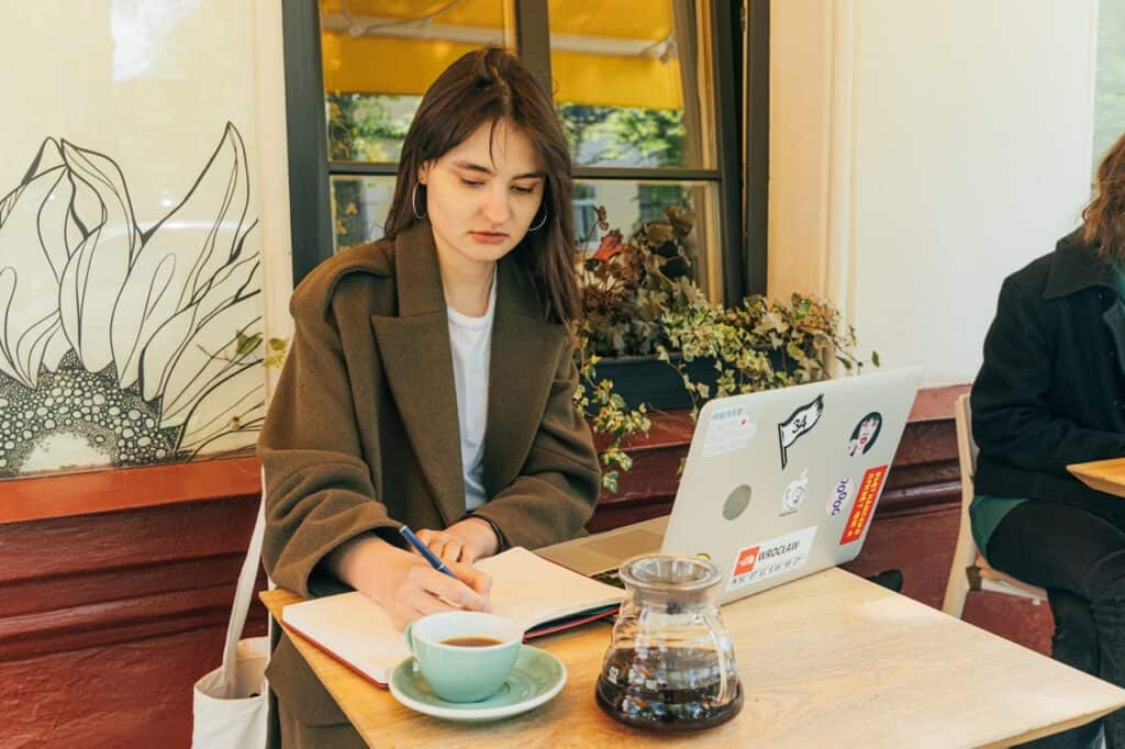 Traveler writing postcard café table