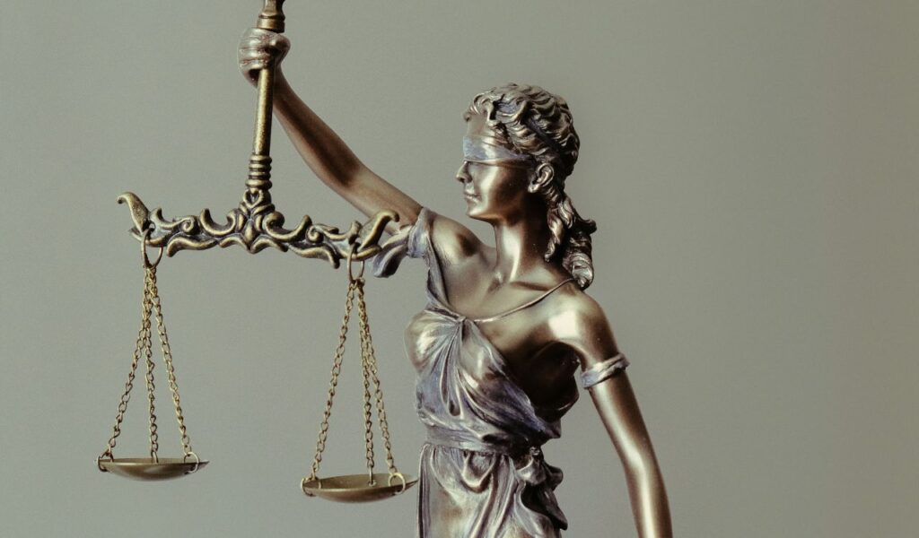 Bronze statue of Lady Justice holding balanced scales, wearing a blindfold, symbolizing fairness and law.