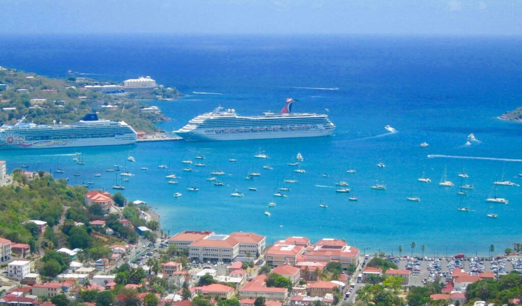 Aerial view of St. Thomas, U.S. Virgin Islands, with cruise ships docked at the harbor, sailboats in turquoise waters, and a town with red-roofed buildings in the foreground