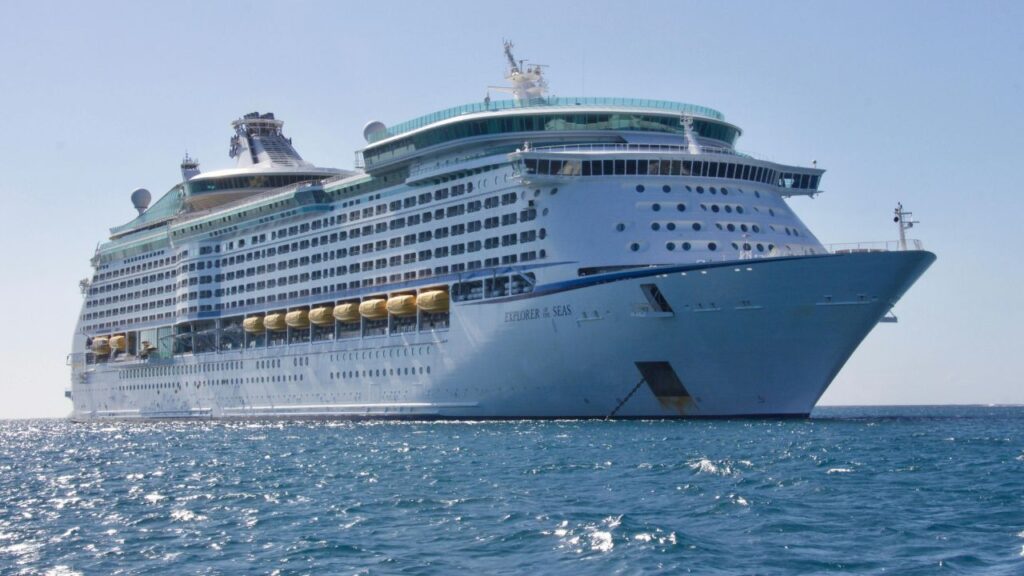 A large white cruise ship named Explorer of the Seas sailing on calm blue waters under a clear sky