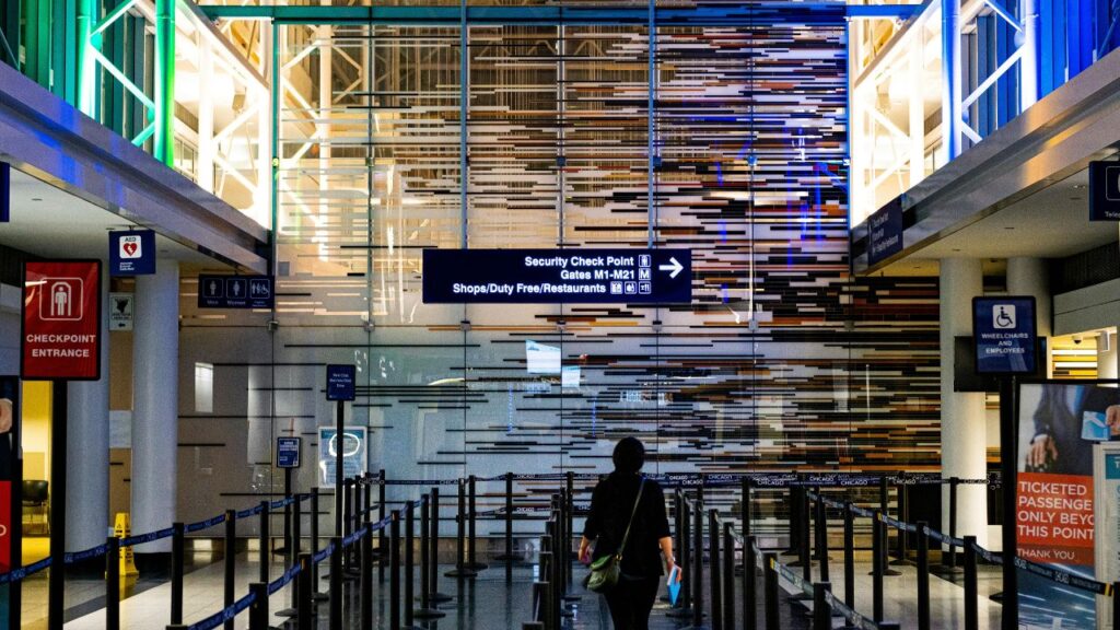 Traveler walking toward TSA security checkpoint at a modern airport with illuminated signage and empty PreCheck lanes.