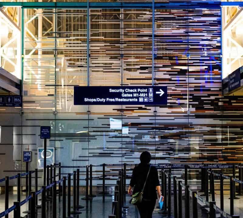 Traveler walking toward TSA security checkpoint at a modern airport with illuminated signage and empty PreCheck lanes.