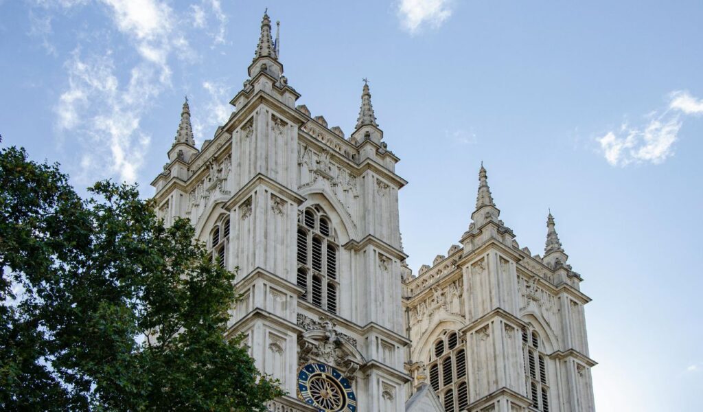 Close-up view of Westminster Abbey’s twin Gothic towers in London, England, with intricate stone detailing and a clock above the main entrance.