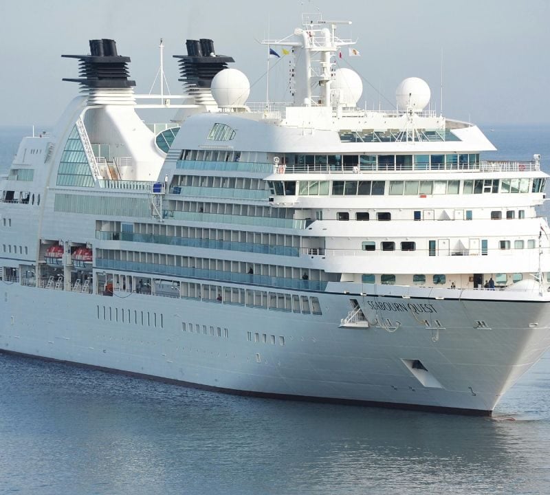 Large white cruise ship named Seabourn Quest sailing on calm blue waters under a clear sky.