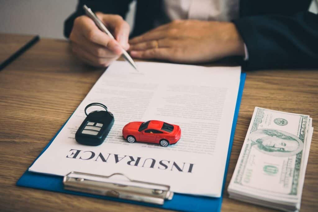 Close-up of hands holding car keys and insurance papers.