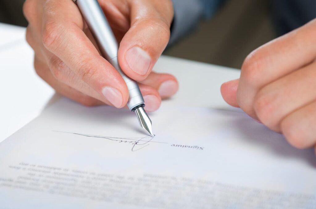 Close-up of hands signing a rental agreement.