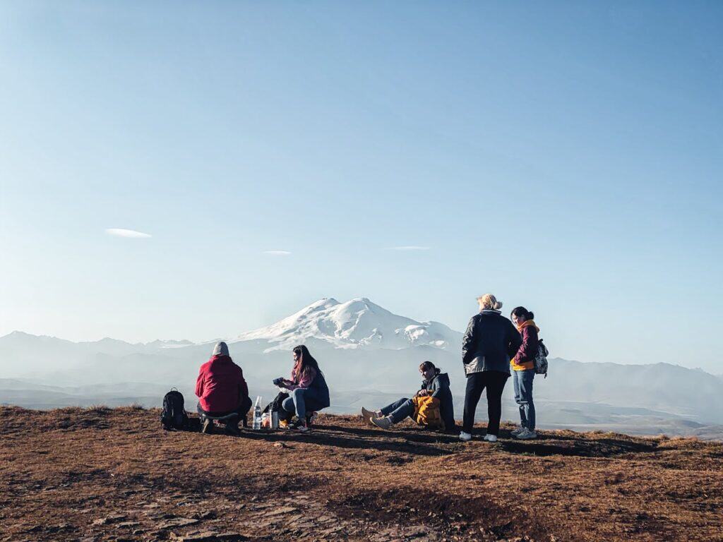 Flat-lay or picnic shot of energy bars, nuts, fruits, and simple trail food laid out on a rock by a mountain vista.