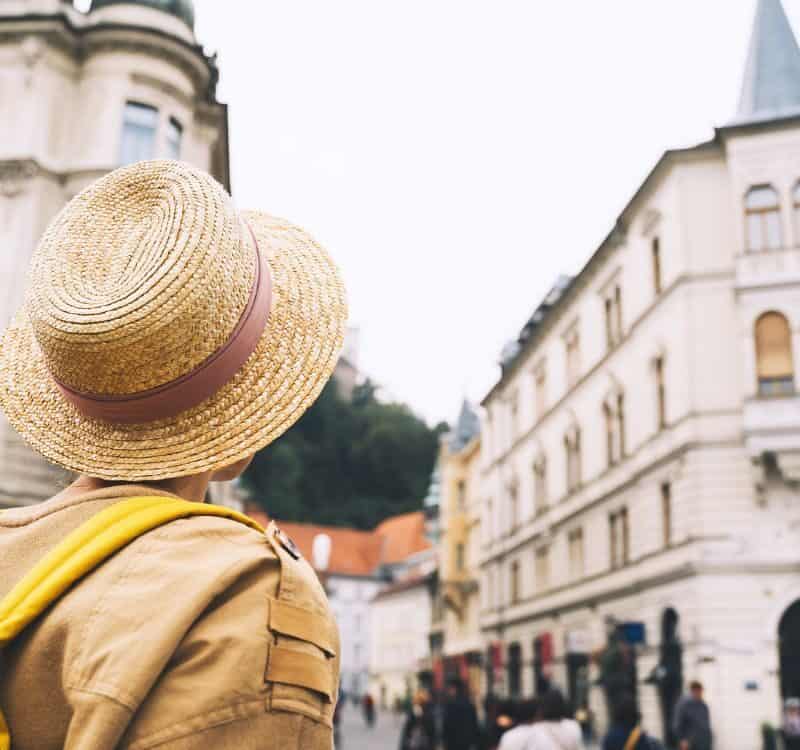 Travel Slovenia, Europe. Young girl with backpack on Triple Bridge in heart of Ljubljana Old Town. Back view of woman tourist on the background of city architecture. Local living in Ljubljana