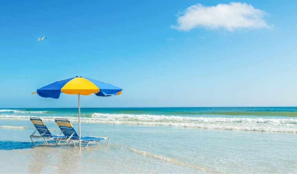 Two beach chairs and a parasol on the sand in a tropical beach