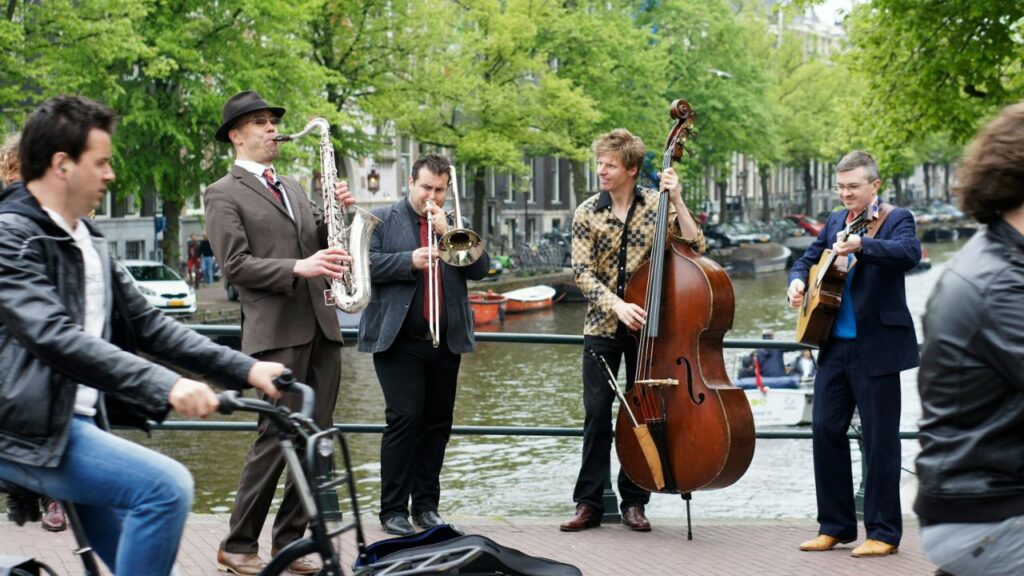 Musician with cello crossing a canal bridge in Amsterdam