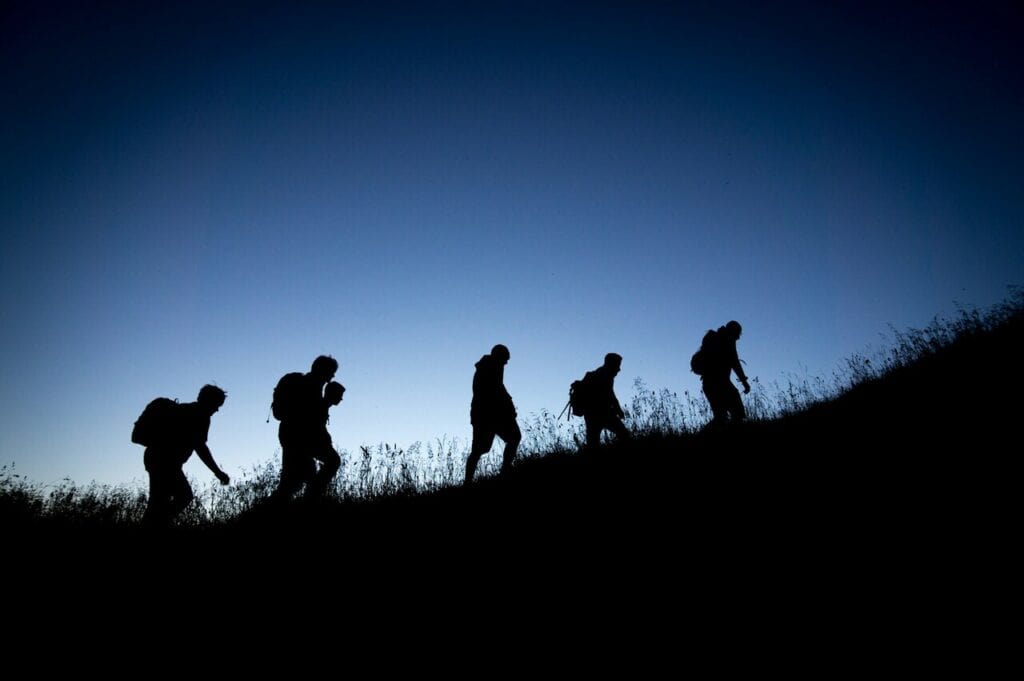 Wide shot of trekkers walking at staggered intervals on a long incline, 