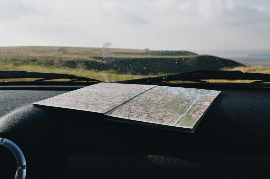 “road atlas open on car dashboard”