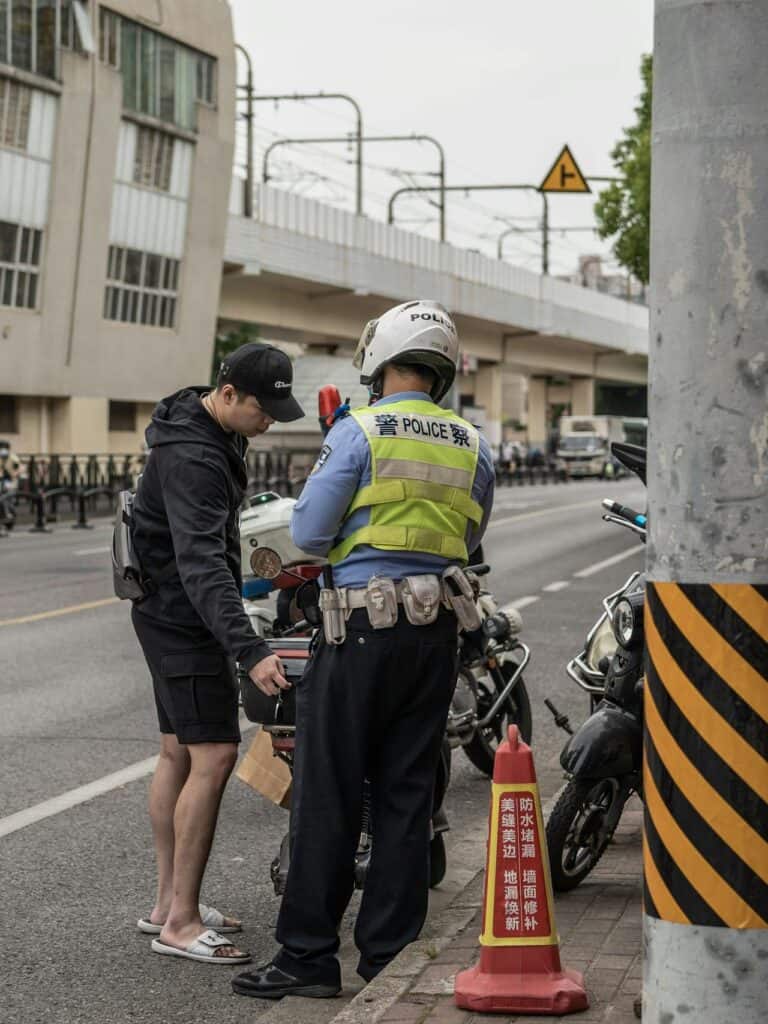 A ticket being written by a police officer next to a motorcycle.