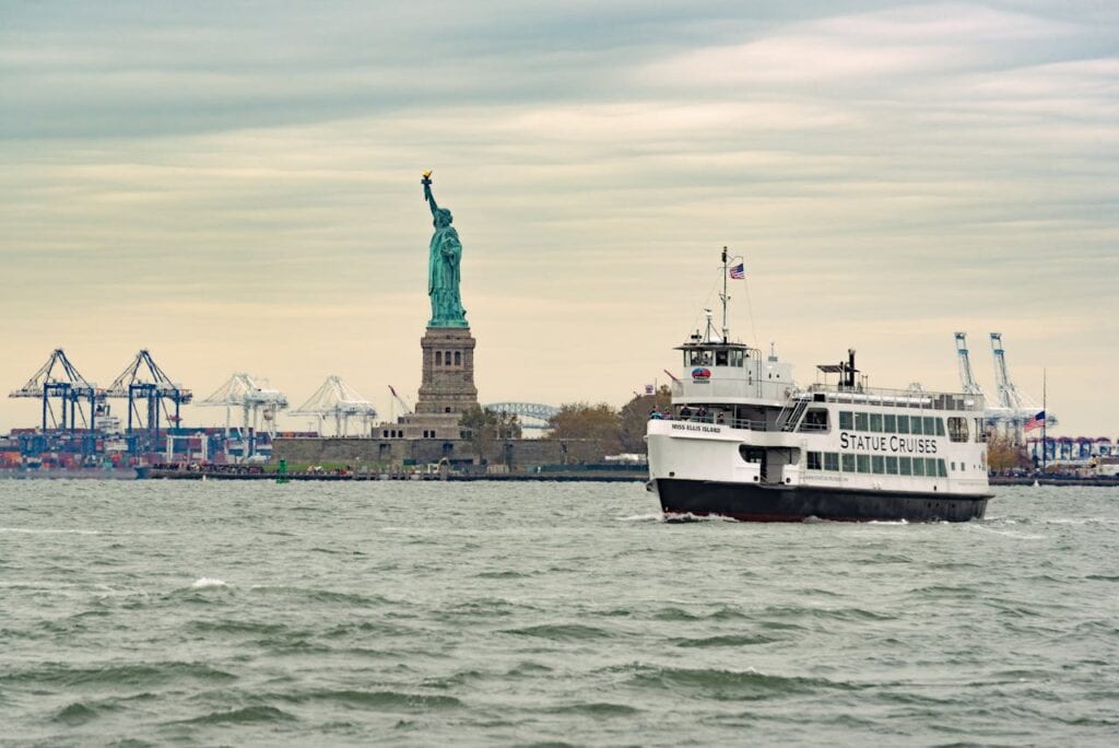 A wide-angle shot of the Staten Island Ferry passing the Statue of Liberty