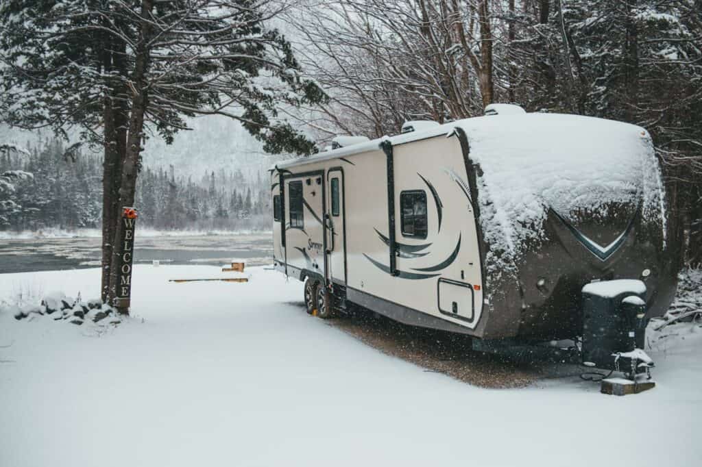 Snow-dusted RV campsite with frozen hoses and propane tanks