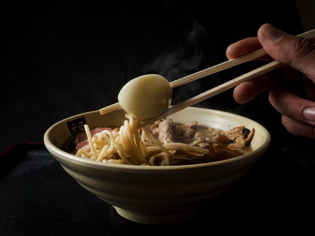 Fingers Holding Food in Chopsticks