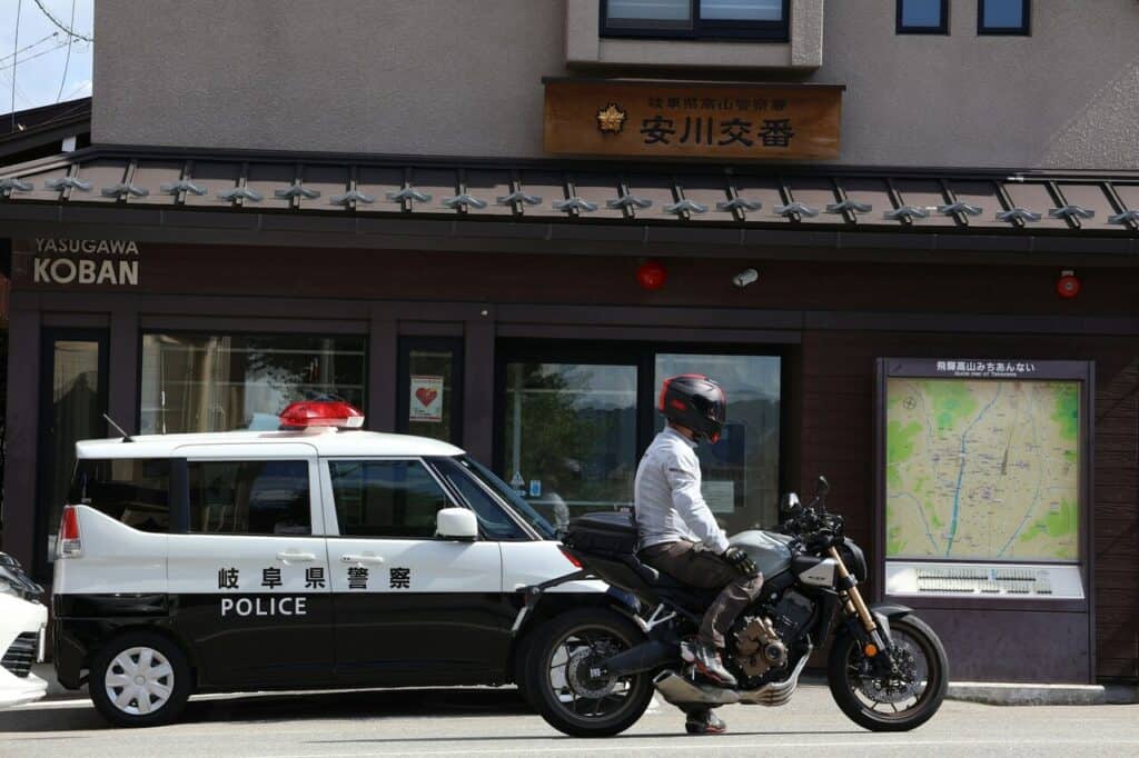 A police car stopped at an intersection where a motorcycle is waiting.