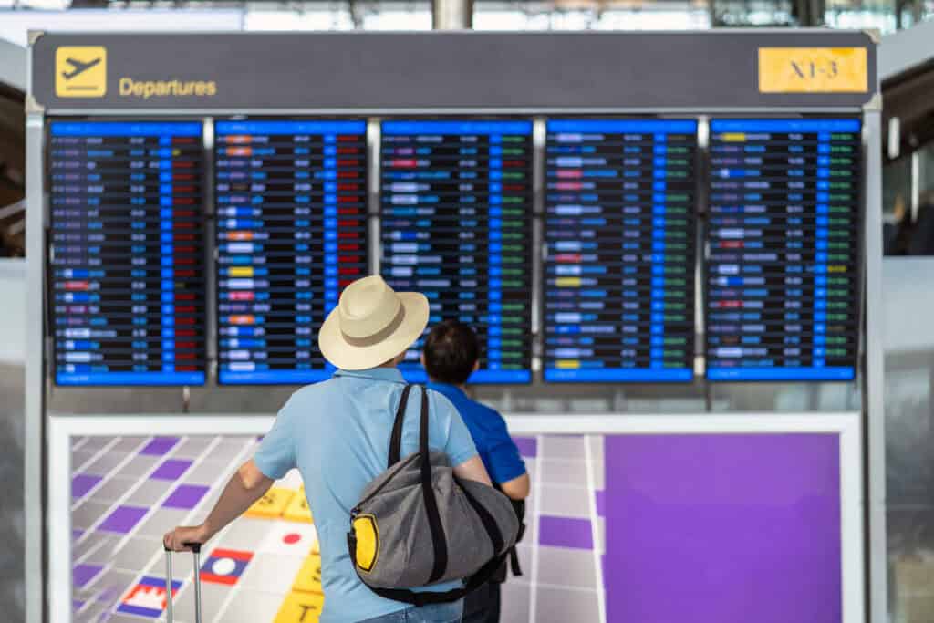 silhouette of traveler looking at departure board in airport