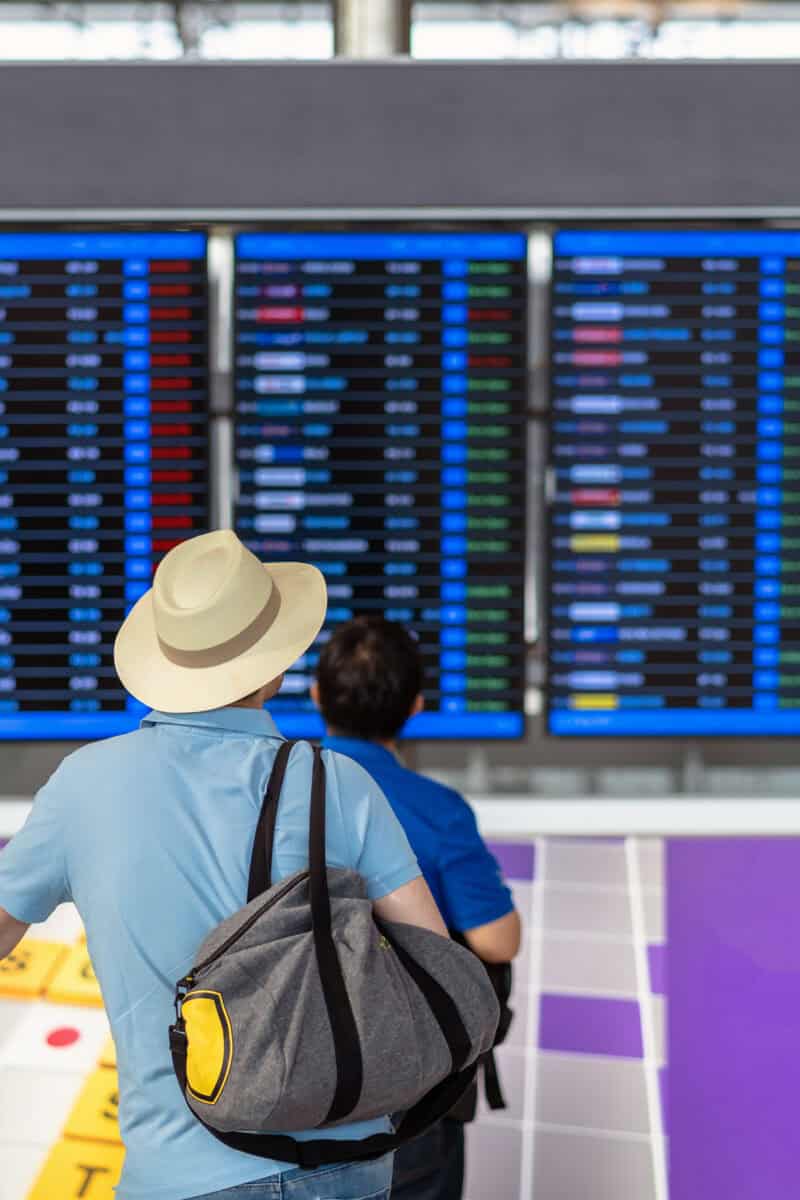 silhouette of traveler looking at departure board in airport