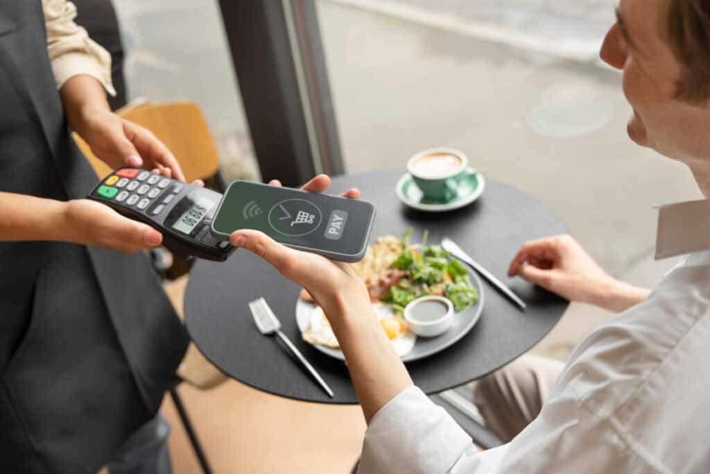 Customer tapping a smartphone or contactless card at a restaurant terminal