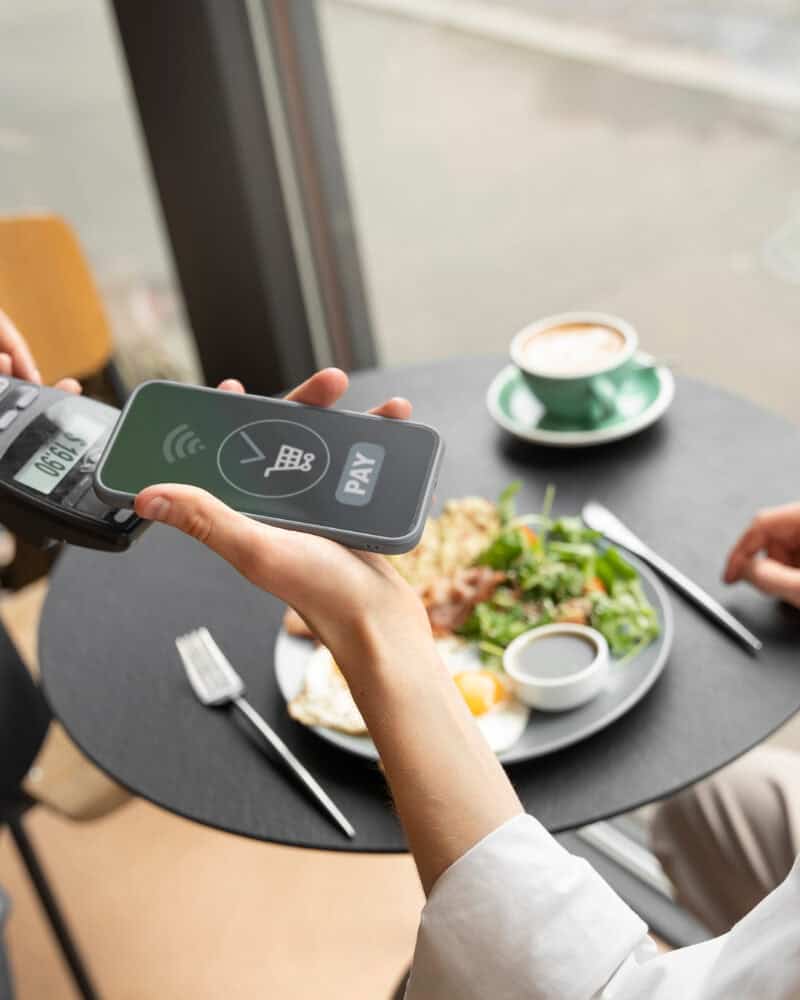 Customer tapping a smartphone or contactless card at a restaurant terminal