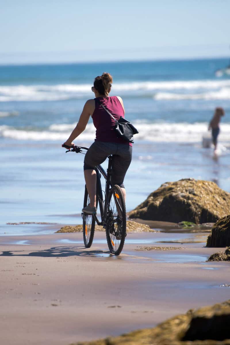Girl enjoys cycling along beach road island sunset