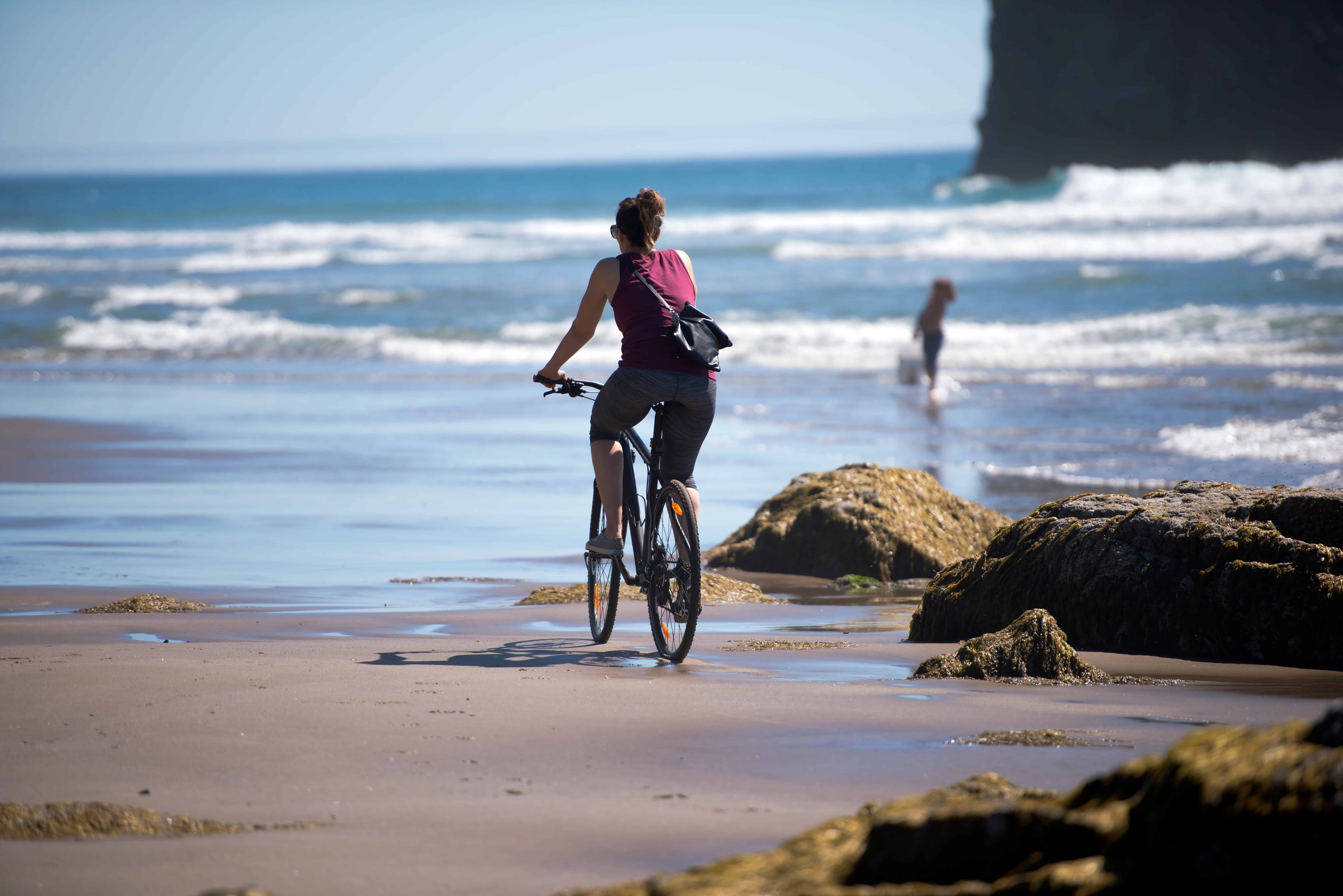 Girl enjoys cycling along beach road island sunset