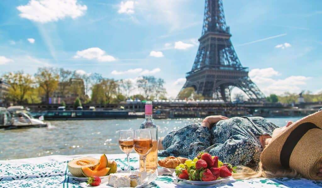 A woman near the Eiffel Tower drinks wine. Selective focus. People.