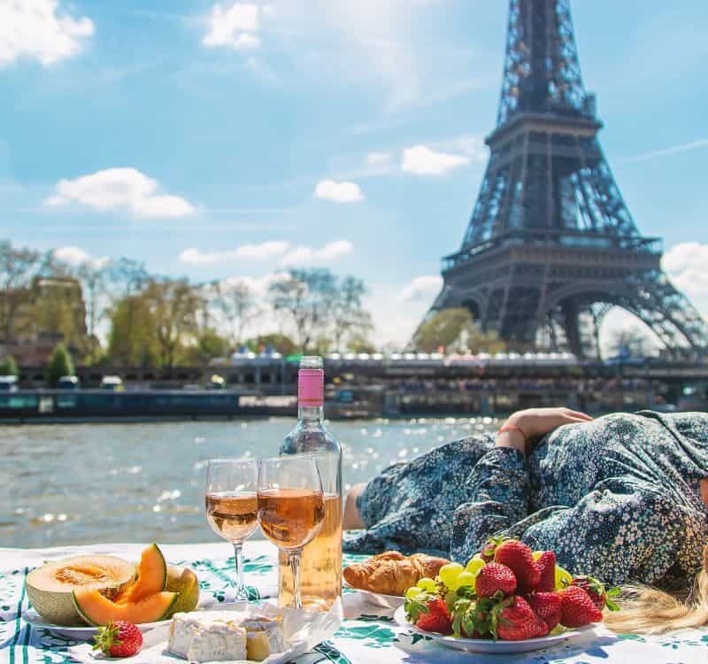 A woman near the Eiffel Tower drinks wine. Selective focus. People.