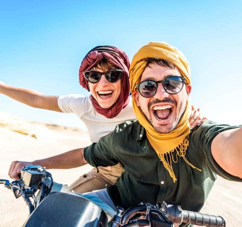 Young couple on a off road adventure excursion outside - Joyful tourists taking selfie with smart mobile phone in the desert