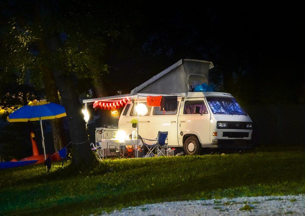 A camper retracting their awning at sunset.