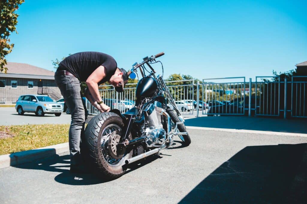 rider checking motorcycle tire pressure with gauge