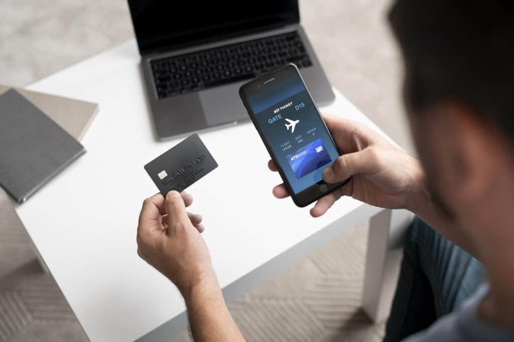 hands holding travel card and smartphone banking app