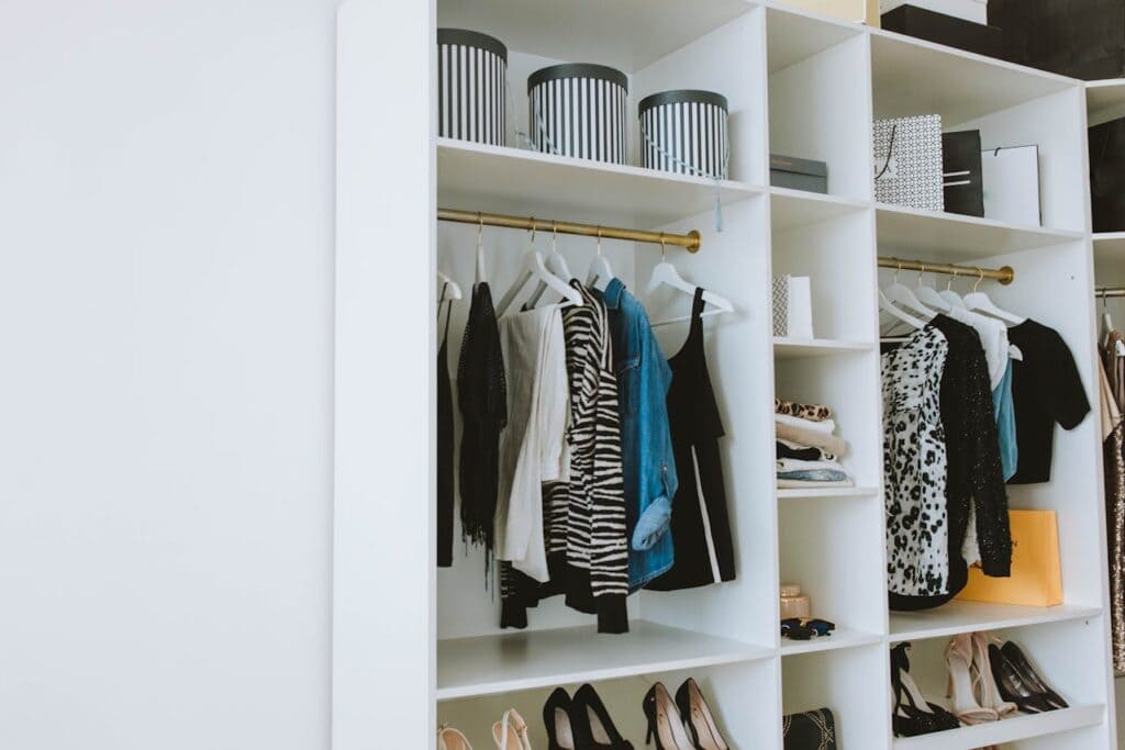 A small, neatly arranged wardrobe with a few quality clothing items hanging.