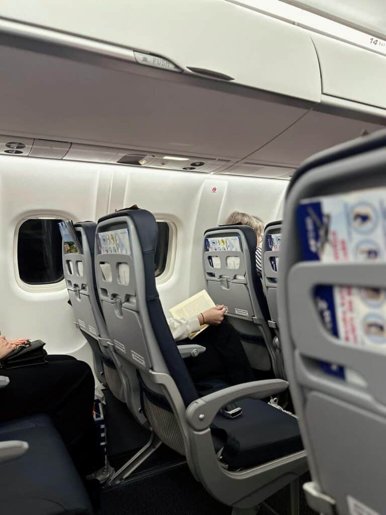 Passenger already unpacking belongings into the seat pocket.