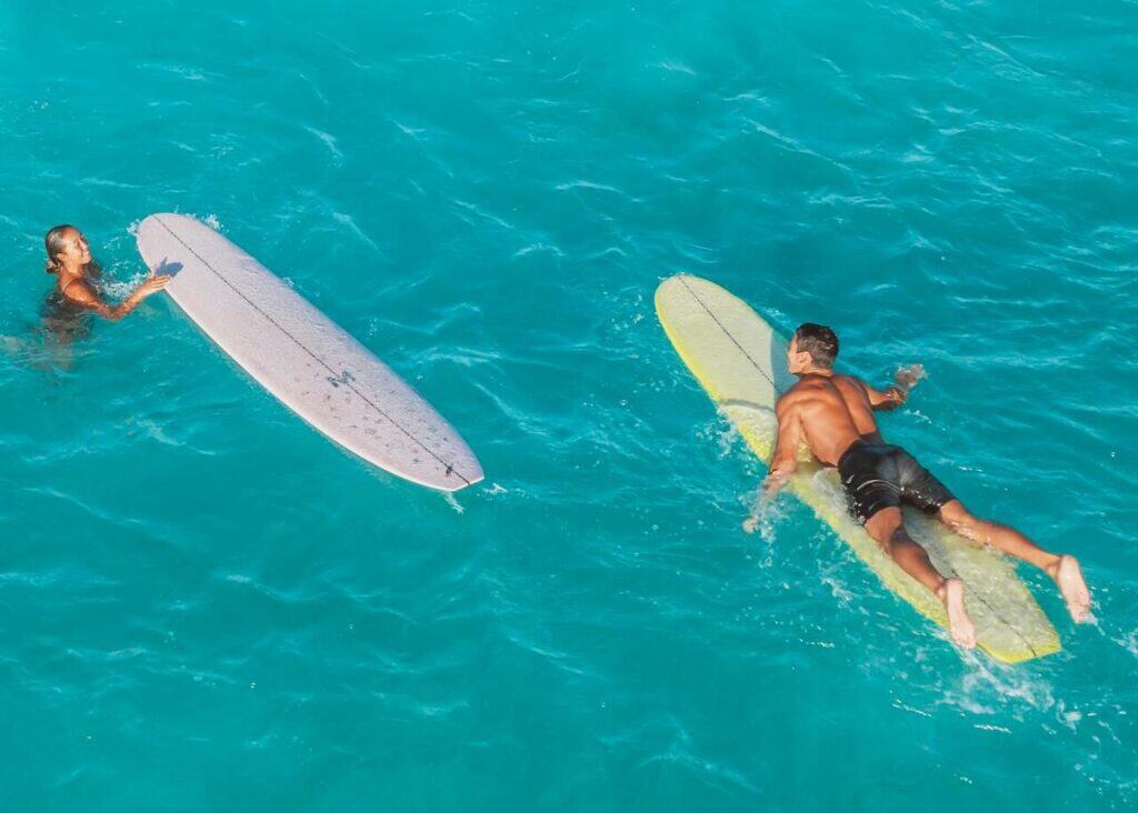 Two Surfboards and a Man in Turquoise Water