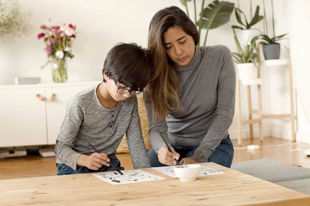 A parent helping a child dial a number while looking at a notebook.