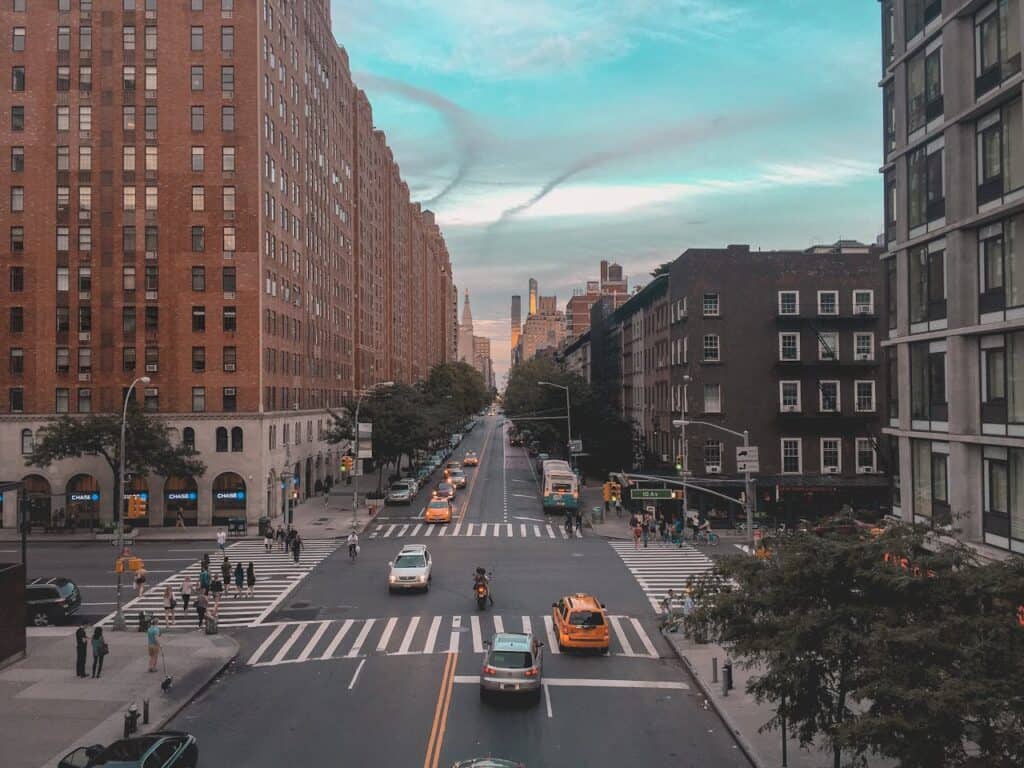 Pedestrians crossing a street at a marked crosswalk with traffic lights visible.