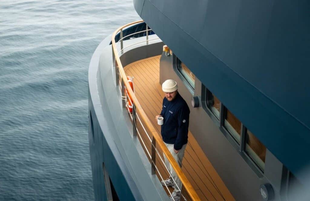 Retirees enjoying coffee on a ship balcony with the ocean in the background.