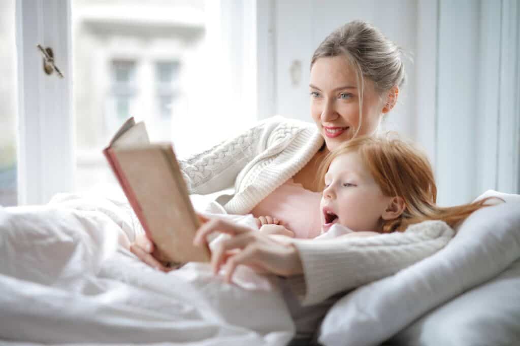 Children under blankets with a flashlight, listening to a story.