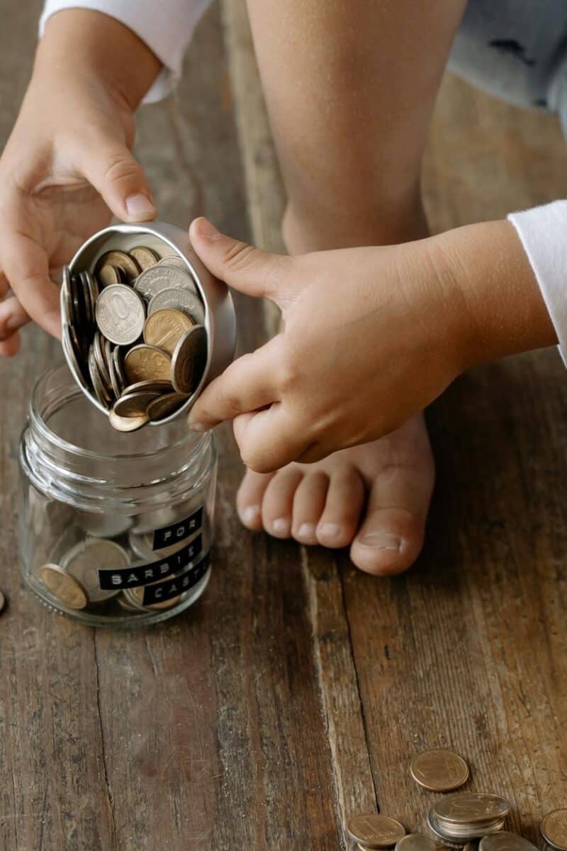 a person putting the coins inside the glass jar