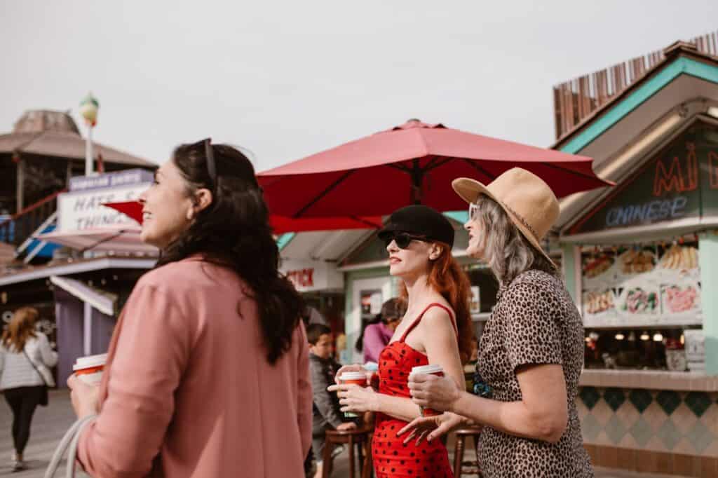  Tourists holding plastic cups with drinks while walking 