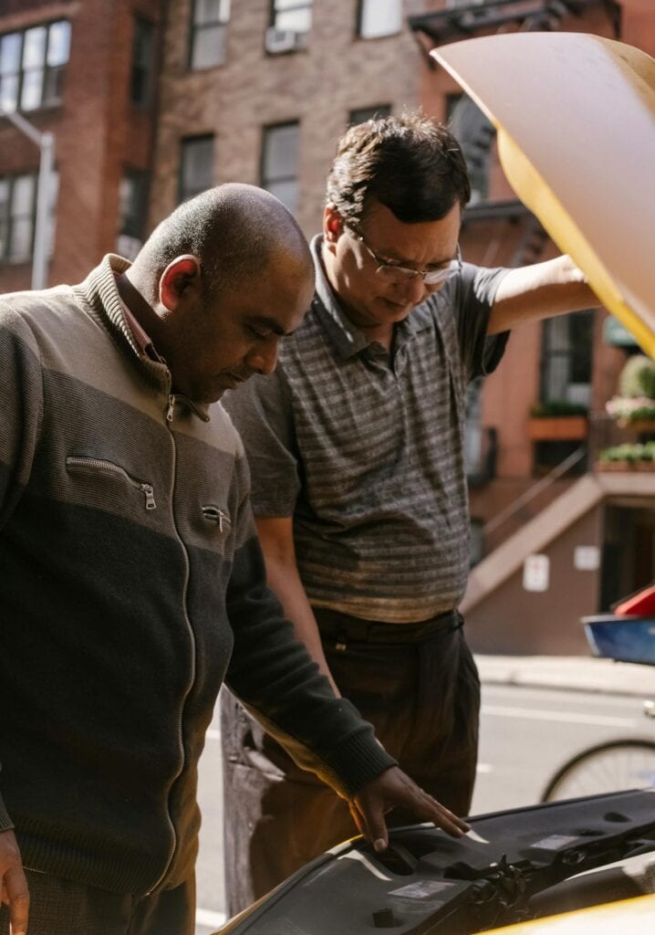 Technician lubricating hitch or checking wheel bearings.